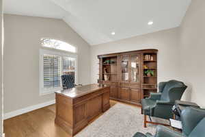 Office space with vaulted ceiling, light wood-style floors, and recessed lighting