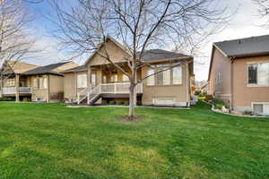 Back of house featuring a lawn and stucco siding