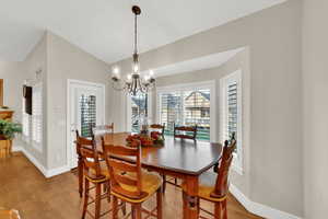 Dining space with light wood-type flooring, vaulted ceiling, and a chandelier