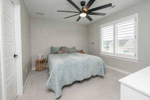 Bedroom with light colored carpet and a ceiling fan