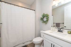 Full bathroom featuring vanity, shower / bath combo, and dark wood-style floors
