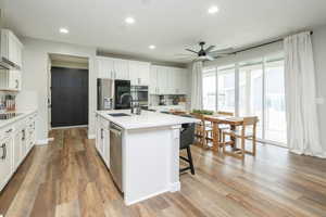 Kitchen with white cabinets, stainless steel appliances, a center island with sink, recessed lighting, and ceiling fan