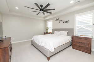 Bedroom with a tray ceiling, light carpet, ceiling fan, and recessed lighting