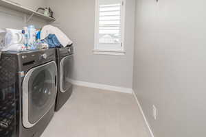 Washroom with washing machine and clothes dryer and tile patterned floors