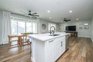 Kitchen with dark wood-type flooring, white cabinetry, open floor plan, a center island with sink, and ceiling fan