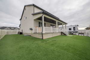 Back of house with a fenced backyard and a porch