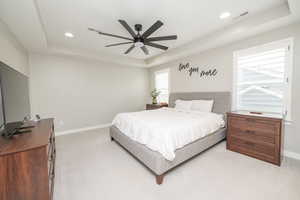 Bedroom featuring a tray ceiling, a ceiling fan, light colored carpet, and recessed lighting
