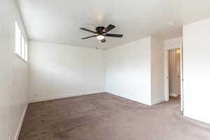 Extra large primary room featuring a ceiling fan and baseboards