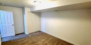 Unfurnished bedroom featuring dark carpet, a closet, and a textured ceiling