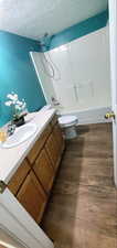 Full bathroom featuring vanity, a textured ceiling, tub / shower combination, and wood finish floors