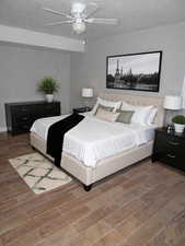 Bedroom featuring wood finish floors, a ceiling fan, and a textured ceiling