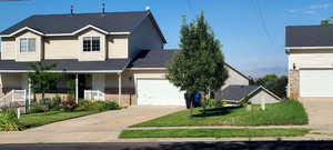 Traditional-style home featuring covered porch, brick siding, a front yard, roof with shingles, and concrete driveway