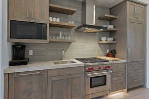 Kitchen with open shelves, wall chimney range hood, premium stove, built in microwave, and backsplash