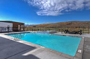 View of pool featuring a patio area, a mountain view, and a pool with connected hot tub