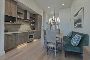 Kitchen with open shelves, light countertops, decorative backsplash, wall chimney range hood, and luxury stove