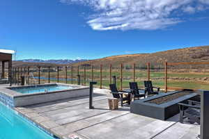 Swimming pool with a fire pit, a mountain view, an in-ground hot tub, and a patio