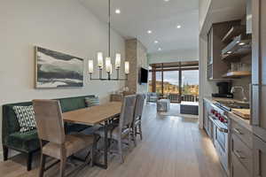 Dining room with recessed lighting, light wood-style flooring, a high ceiling, and a chandelier