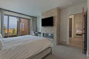 Bedroom with access to outside, a stone fireplace, and carpet
