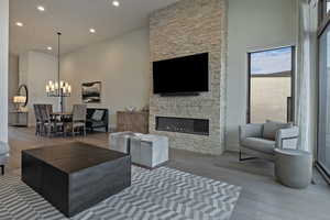 Living area with wood-type flooring, recessed lighting, a stone fireplace, and a towering ceiling