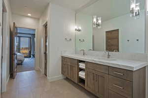 Ensuite bathroom with double vanity, light tile patterned floors, and recessed lighting