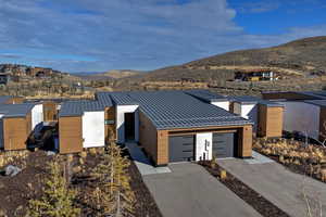 Contemporary house with a standing seam roof, a metal roof, concrete driveway, a mountain view, and an attached garage