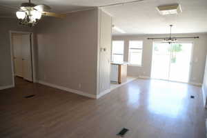Unfurnished living room with a chandelier, light wood-type flooring, and ornamental molding