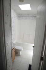 Bathroom featuring vanity, a skylight, light tile patterned floors, shower / washtub combination, and wallpapered walls