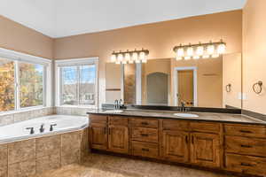 Bathroom with double vanity, a bath, and light tile patterned flooring