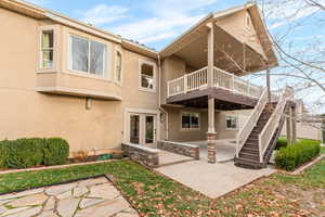 Back of house featuring a patio, stucco siding, stairs, and a deck