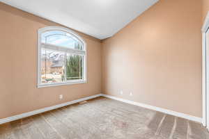 Spare room featuring vaulted ceiling and light colored carpet