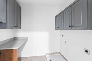 Laundry room featuring hookup for an electric dryer, light tile patterned floors, and cabinet space