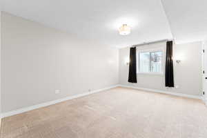 Empty room featuring a textured ceiling and light colored carpet