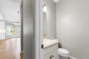 Half bathroom featuring vanity, light wood finished floors, and a chandelier