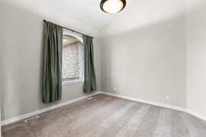 Carpeted empty room with lofted ceiling and baseboards