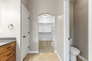 Full bathroom with a spacious closet, vanity, light tile patterned floors, and light carpet