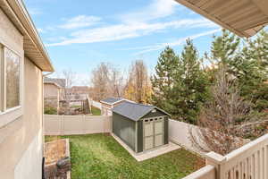 Fenced backyard featuring a storage unit and a balcony