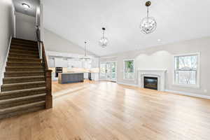 Unfurnished living room with recessed lighting, a fireplace, stairs, light wood-style flooring, and high vaulted ceiling