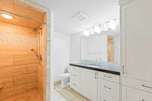 Bathroom featuring vanity, a shower stall, and a textured ceiling