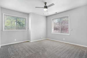 Empty room featuring ceiling fan, carpet flooring, and a textured ceiling
