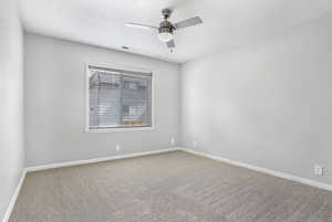 Carpeted spare room featuring baseboards and ceiling fan
