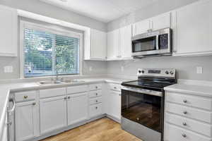 Kitchen featuring appliances with stainless steel finishes, white cabinetry, and light countertops