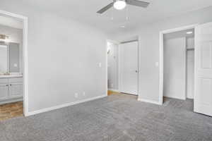 Unfurnished bedroom with light carpet, ensuite bath, a ceiling fan, and a closet