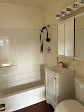 Full bath with shower / bathtub combination, vanity, and dark wood finished floors