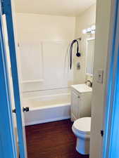 Bathroom with vanity, bathing tub / shower combination, and dark wood-style floors