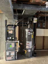 Utility room featuring strapped water heater and heating unit.  New heating unit, A/C, water heater installed in 2025