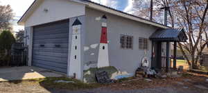View of side of property with a garage, concrete block siding, and an outbuilding