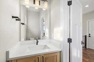 Half bath with vanity and dark wood-type flooring
