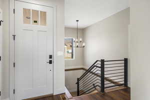 Entrance foyer featuring dark wood-style floors, a chandelier, and stairway