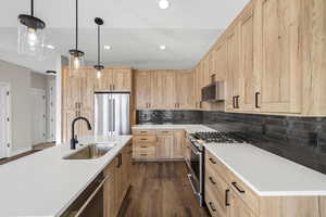 Kitchen featuring light brown cabinetry, stainless steel appliances, decorative backsplash, pendant lighting, and recessed lighting