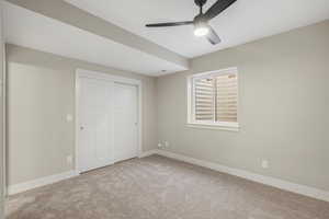 Unfurnished bedroom featuring a closet, light carpet, and ceiling fan